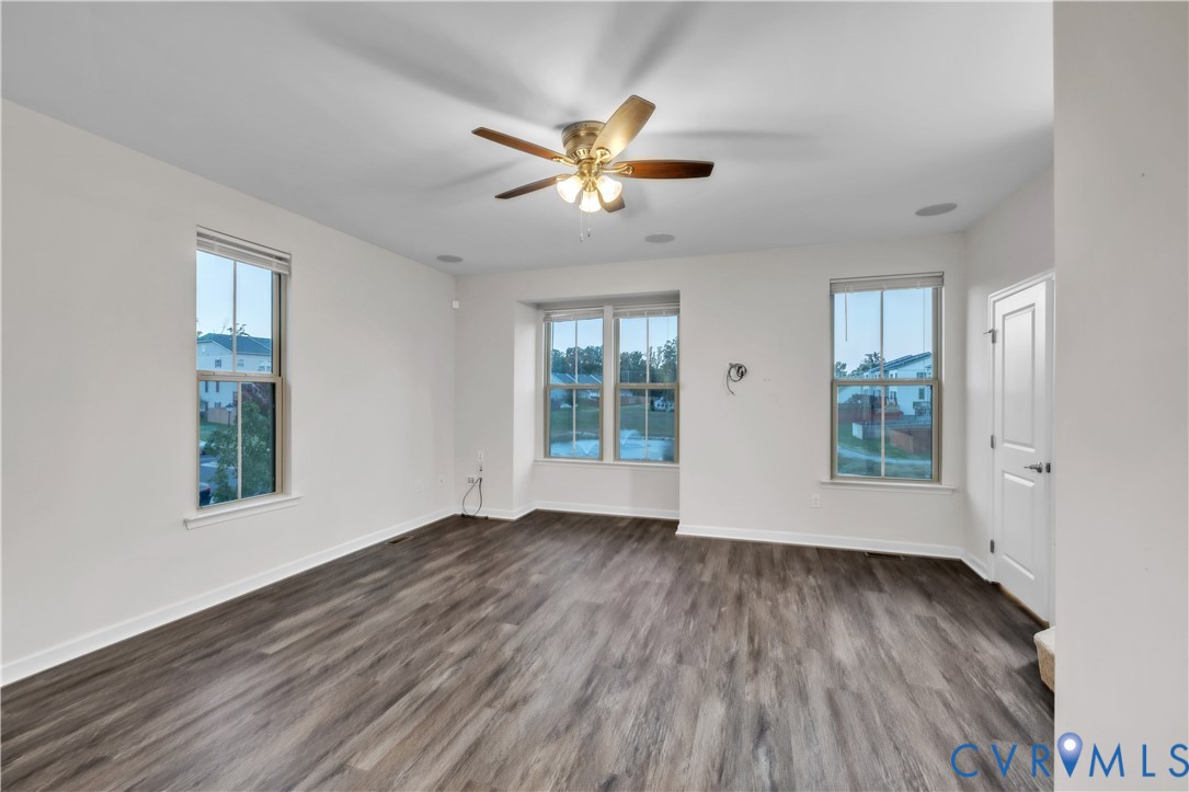 Living space featuring wood-finish flooring, recessed lighting, multi-pane windows, and a central ceiling fan with integrated lighting