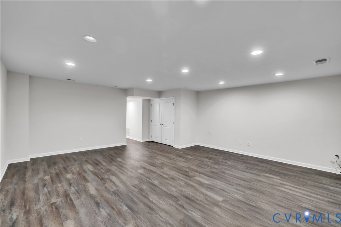 Open-concept interior featuring wood-finish flooring, recessed lighting, and white double-door closet cabinetry