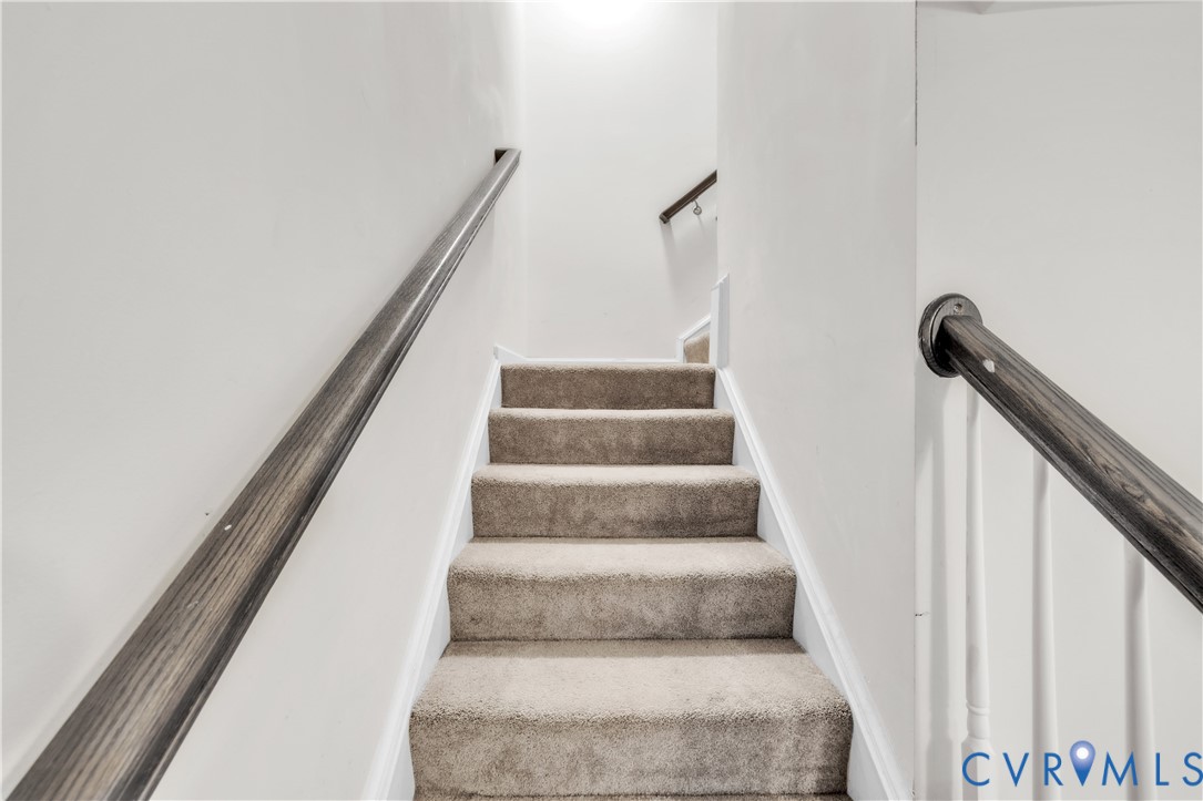Staircase featuring wall-to-wall carpeting, wood-finish handrails, and white balusters