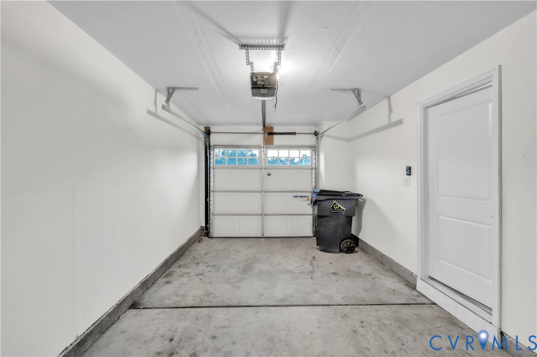 Enclosed garage space featuring a paneled sectional door with integrated window inserts, concrete flooring, and a dedicated side-entry door