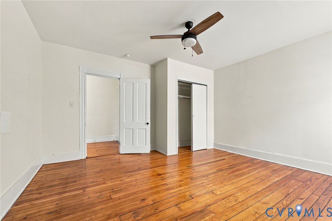 Bedroom #3 with hardwood flooring, wood-finish ceiling fan, and multi-panel interior door