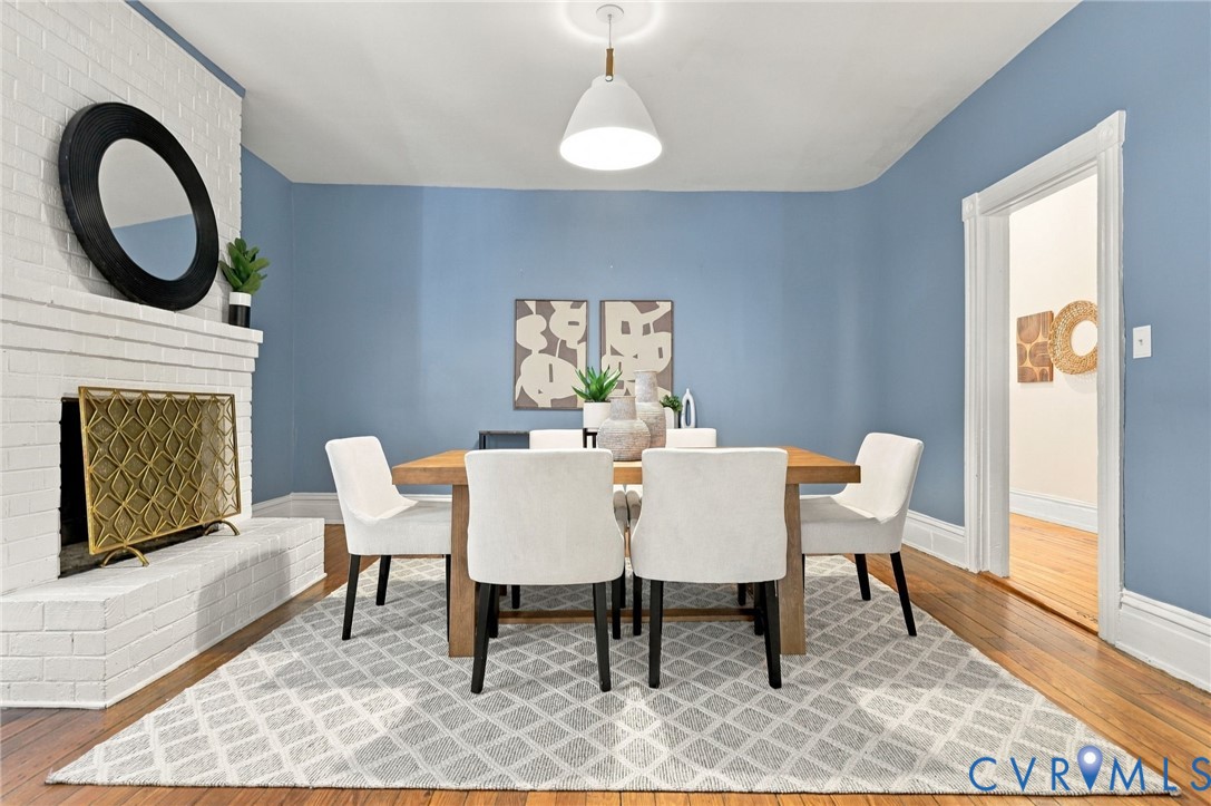White painted brick fireplace, wood-finish flooring, and pendant lighting with view of the corner curved wall.