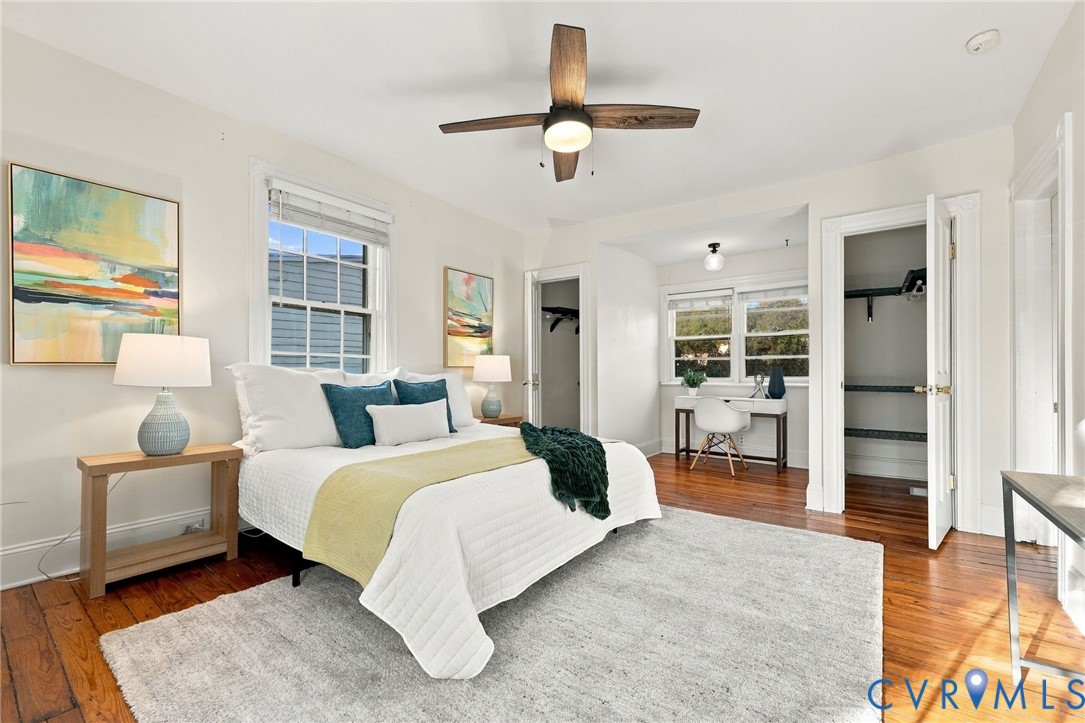 Bedroom featuring wood-finish flooring, multi-pane windows, and a ceiling fan with integrated lighting
