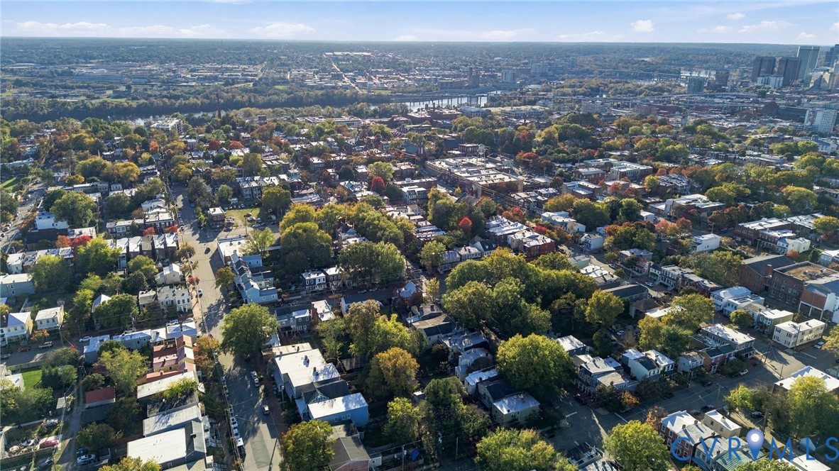 Aerial perspective of a dense urban neighborhood featuring established tree canopy, grid-patterned streets, and proximity to a central business district skyline