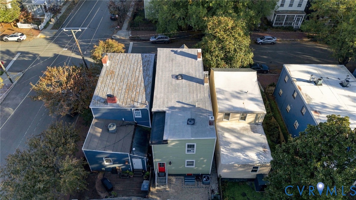 Aerial perspective of the property featuring a multi-level exterior, light green siding, a detached wood deck, and an off-street gravel parking area
