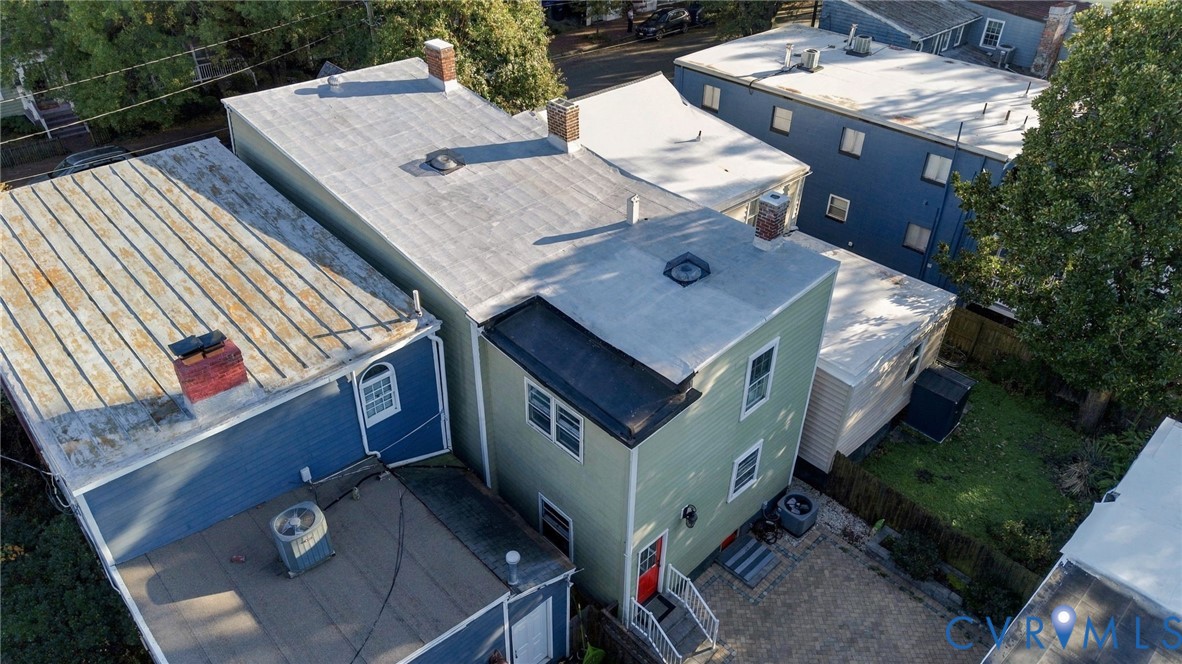 Multi-level exterior featuring light green siding, two rooftop skylights, three brick chimneys, and an outdoor staircase