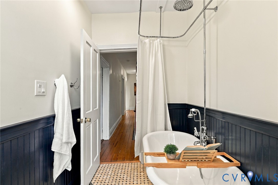 Hall bath w/ Clawfoot soaking tub with a chrome shower assembly, beadboard wainscoting, and mosaic tile flooring