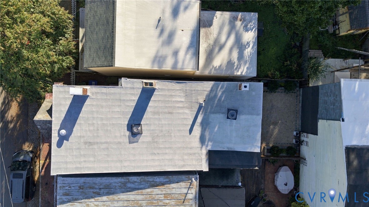 Aerial perspective of the property featuring a flat roof with chimney stacks, two ventilation units, and an area of gravel hardscaping