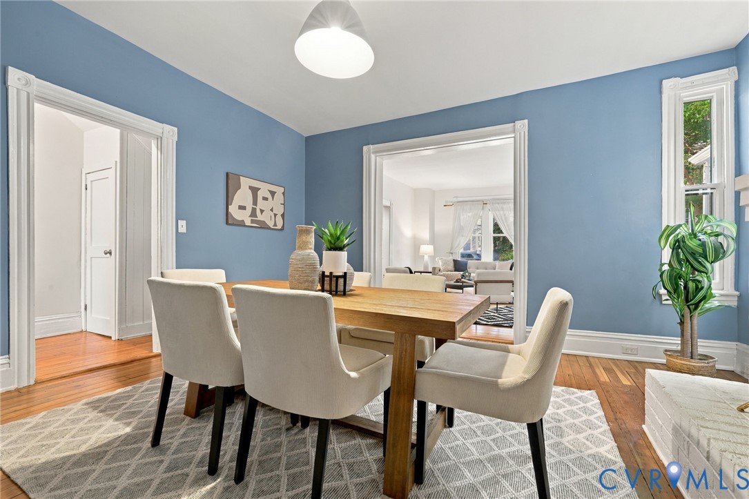 Dining area featuring hardwood flooring, architectural casing around doorways, large windows with millwork trim, and a dome pendant light fixture