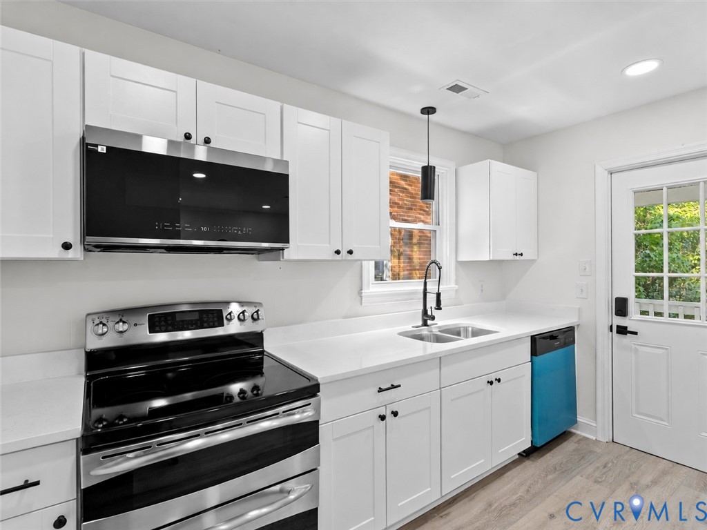 Kitchen featuring white shaker-style cabinetry, solid-surface countertops, a stainless steel range, an over-the-range microwave, and a gooseneck faucet