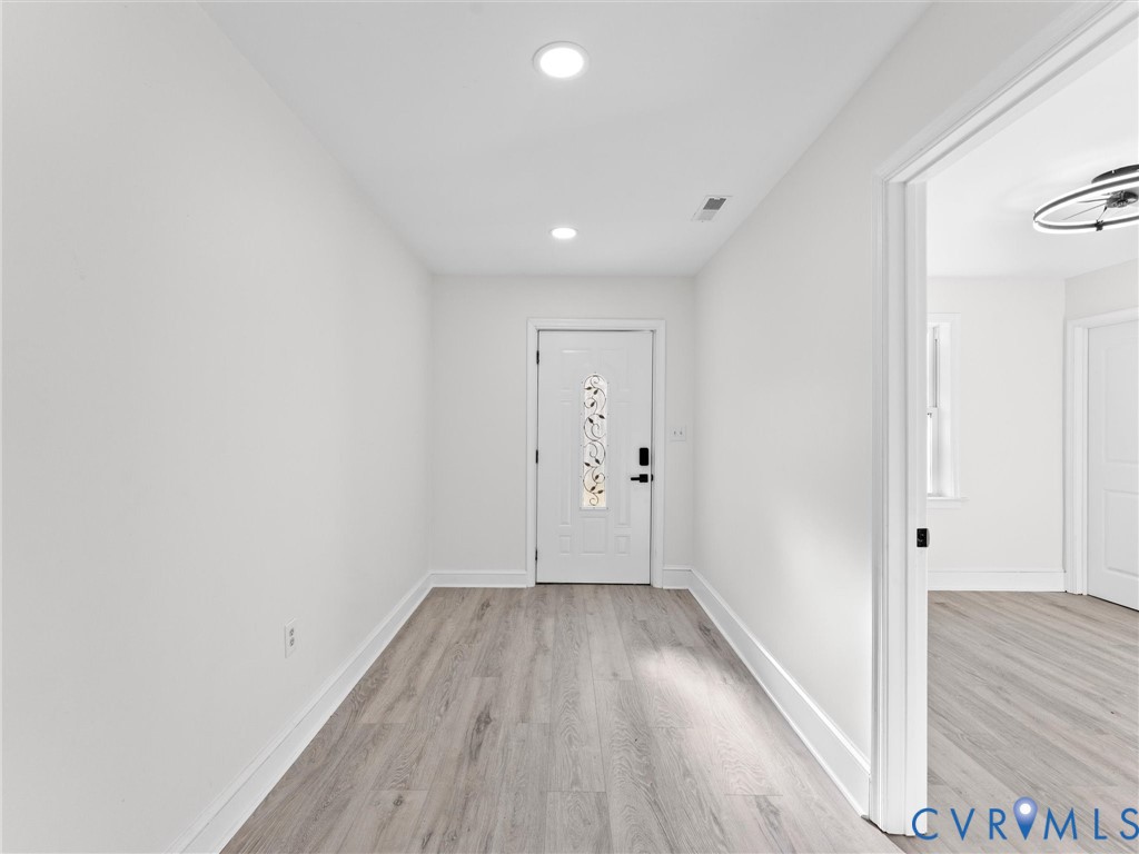 Entryway featuring wood-finish flooring, recessed lighting, and a white exterior door with decorative glass insert
