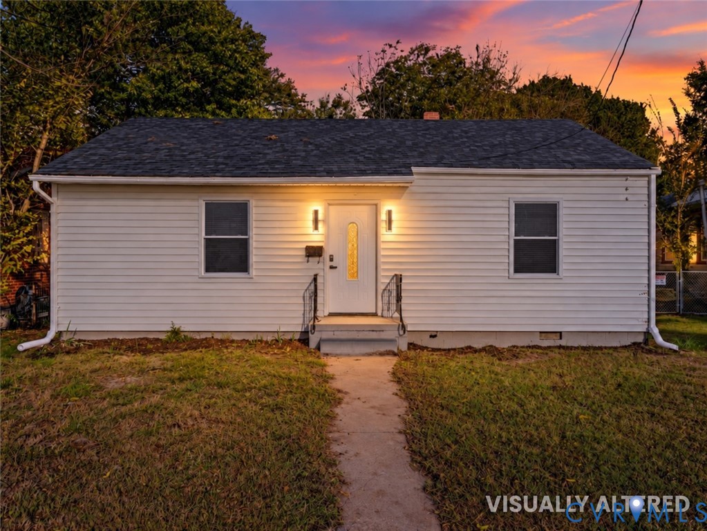 Single-story exterior featuring white horizontal siding, a dark shingle roof, a central front door with a decorative glass insert, and metal handrails