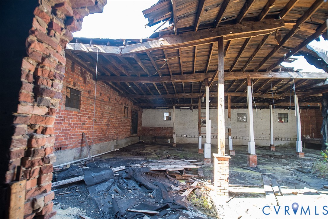 Open-concept structure featuring exposed brick masonry walls, heavy timber roof beams, and vertical wood support columns