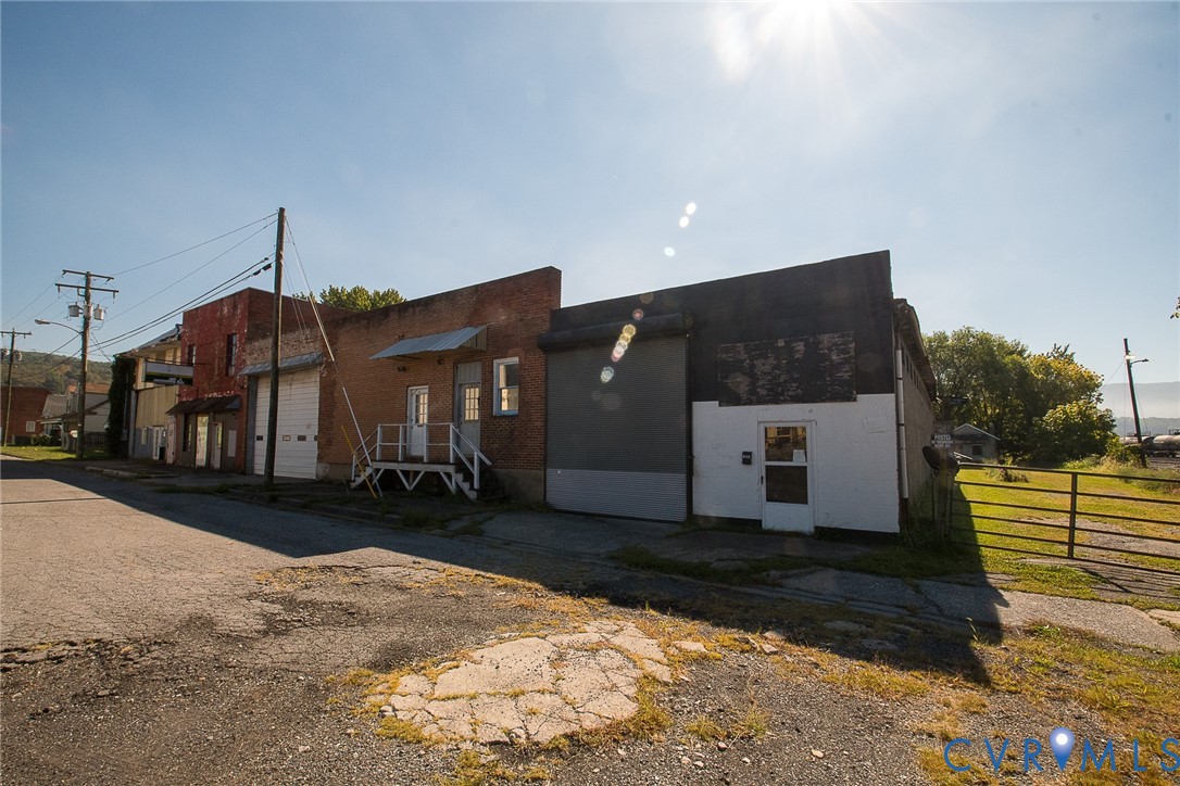 Mixed-use structure featuring brick and masonry exterior, metal rolling bay doors, elevated metal entryway steps, and gated perimeter access