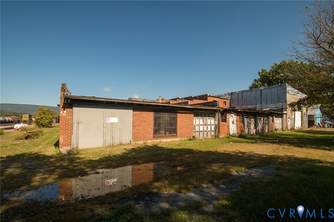 Multi-bay brick structure featuring multiple metal roll-up doors, industrial-style window groupings, and a low-profile flat roof design