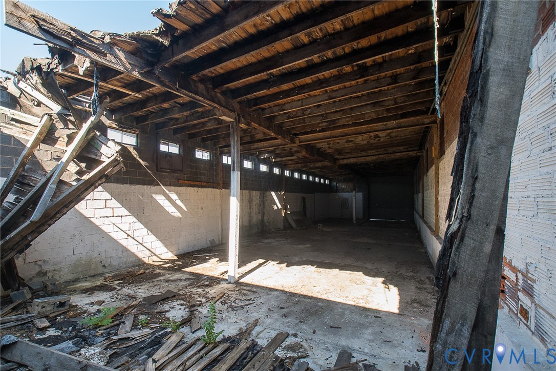 Industrial structure featuring concrete block masonry walls, exposed wood beam ceiling, and a concrete floor
