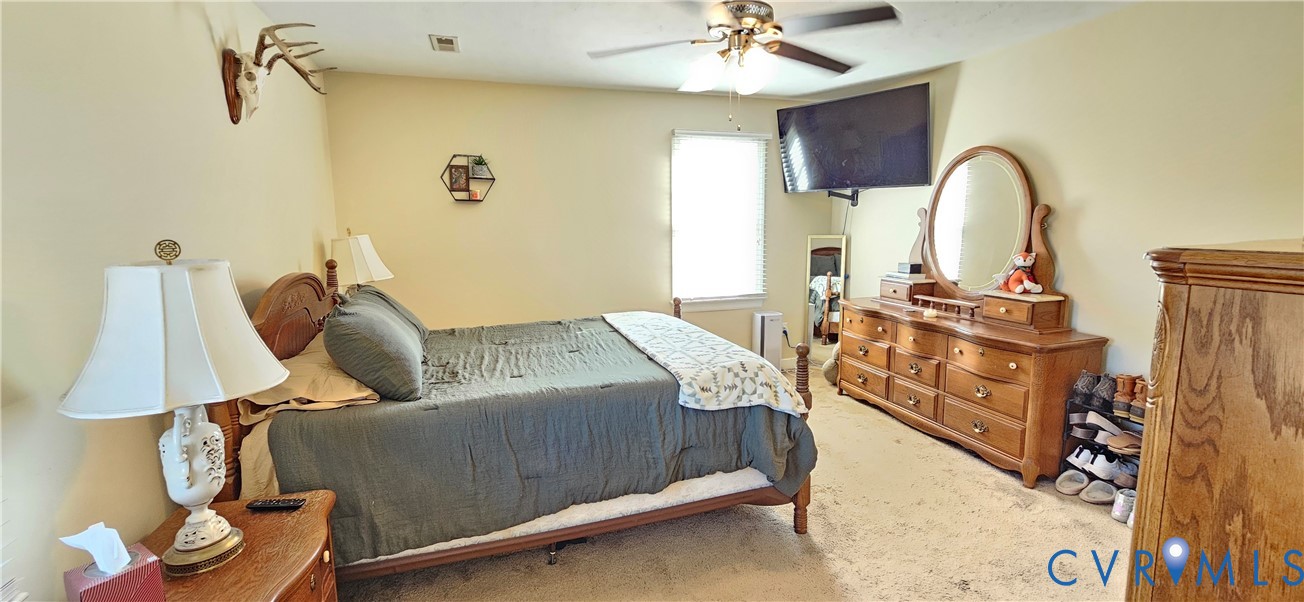 Bedroom featuring neutral wall paint, carpeted flooring, and a ceiling fan with integrated lighting