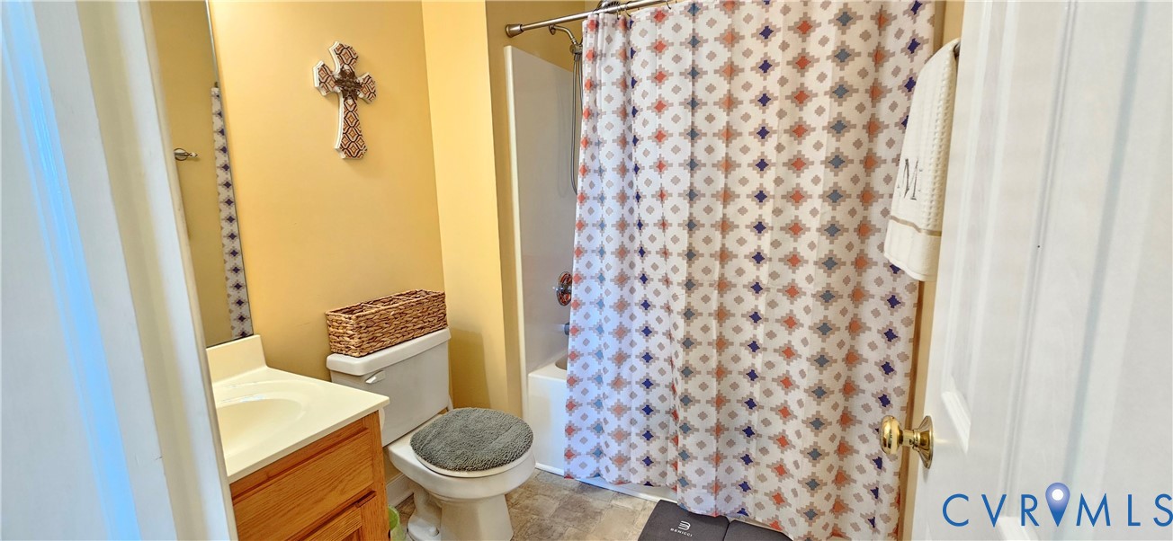 Bathroom featuring a wood-finish vanity with a molded countertop, a built-in wall mirror, a ceramic toilet, and a bathtub-shower combination with a surround