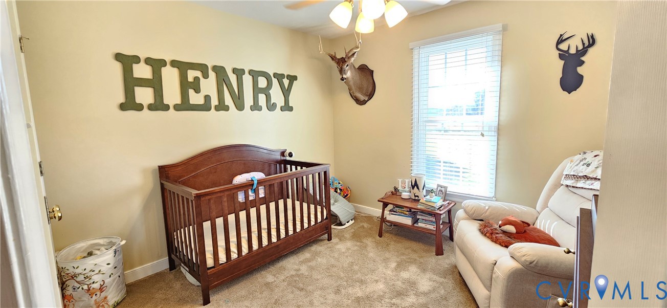 Interior space featuring wall-to-wall carpeting, neutral wall coloring, a multi-bulb ceiling fixture, and a single window with slatted blinds