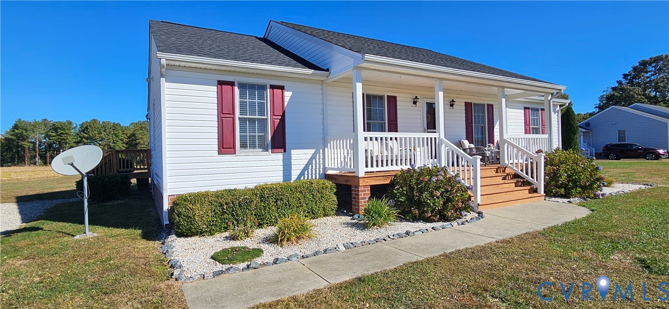 Single-story residence featuring white horizontal siding, a covered front porch with white railing, and decorative red window shutters