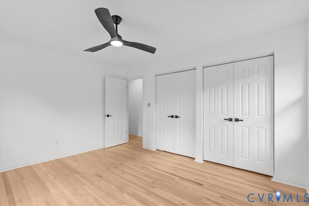 Wood-finish flooring, three-blade ceiling fan with integrated lighting, and white six-panel doors with matte black hardware