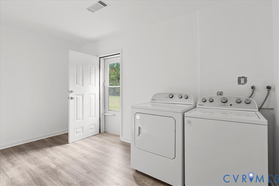Utility room featuring wood-finish flooring, a white paneled door, a single-lite glass exterior door, and dedicated laundry hookups