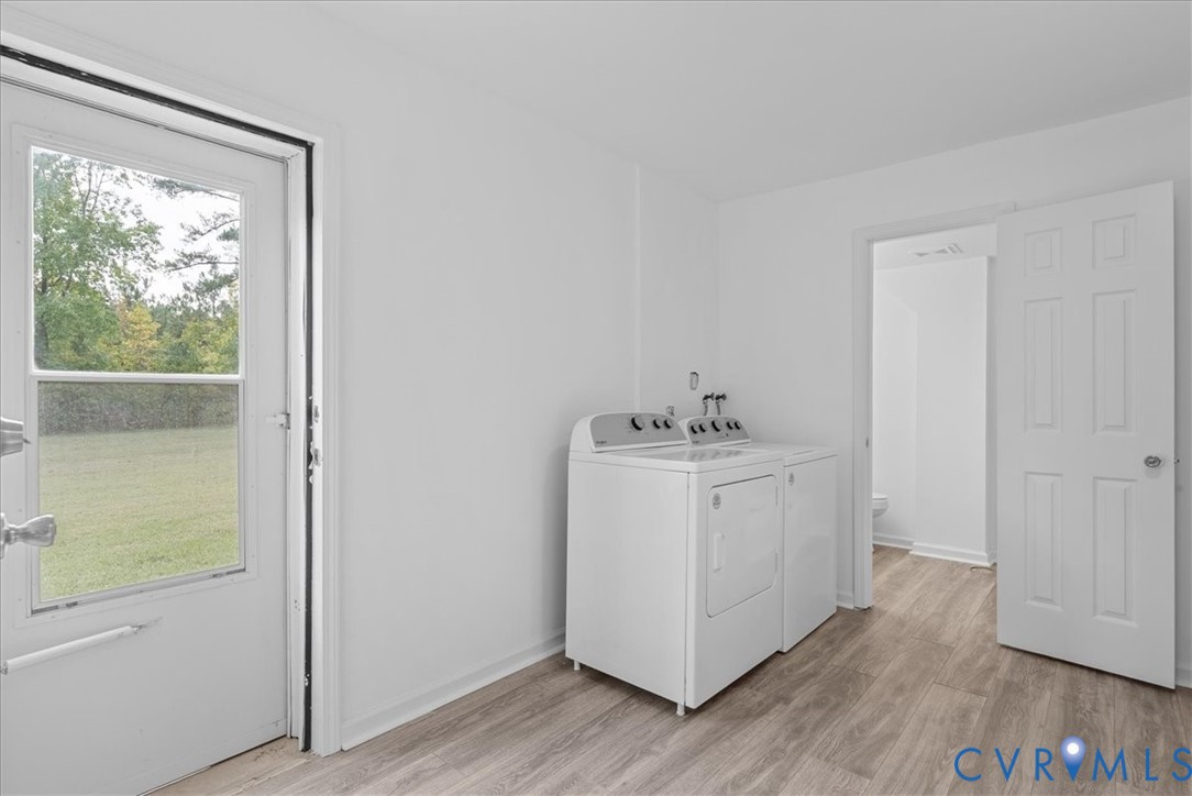 Laundry room featuring wood-finish flooring, a six-panel interior door, and a glass-inset exterior door