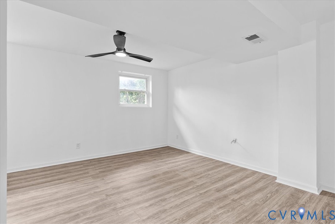 Interior room featuring wood-finish flooring, white walls, and a modern ceiling fan with integrated lighting