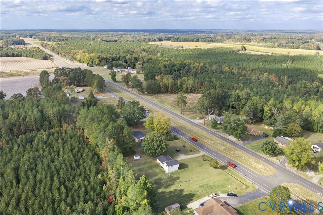 Aerial perspective featuring expansive acreage, mature tree clusters, and direct road access