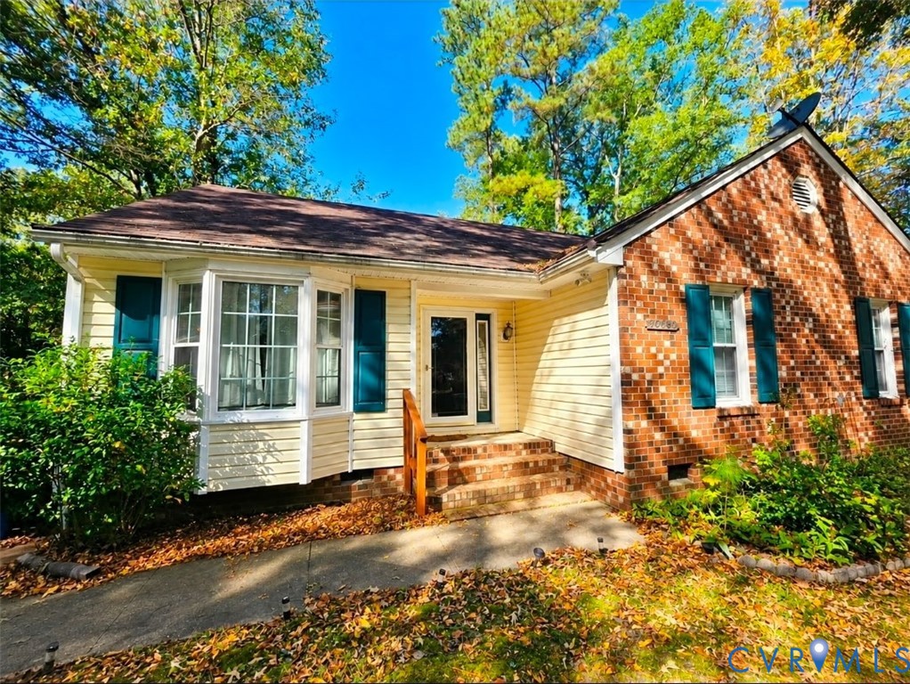 Exterior facade featuring a mix of brick and horizontal siding, a bay window, decorative shutters, and a covered entryway with brick steps