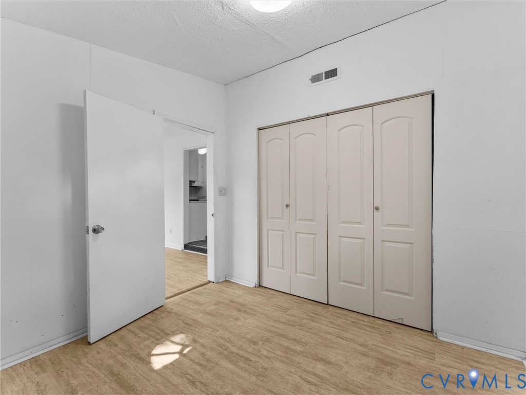 Interior space featuring wood-finish flooring, white walls, and a multi-panel door closet with chrome hardware