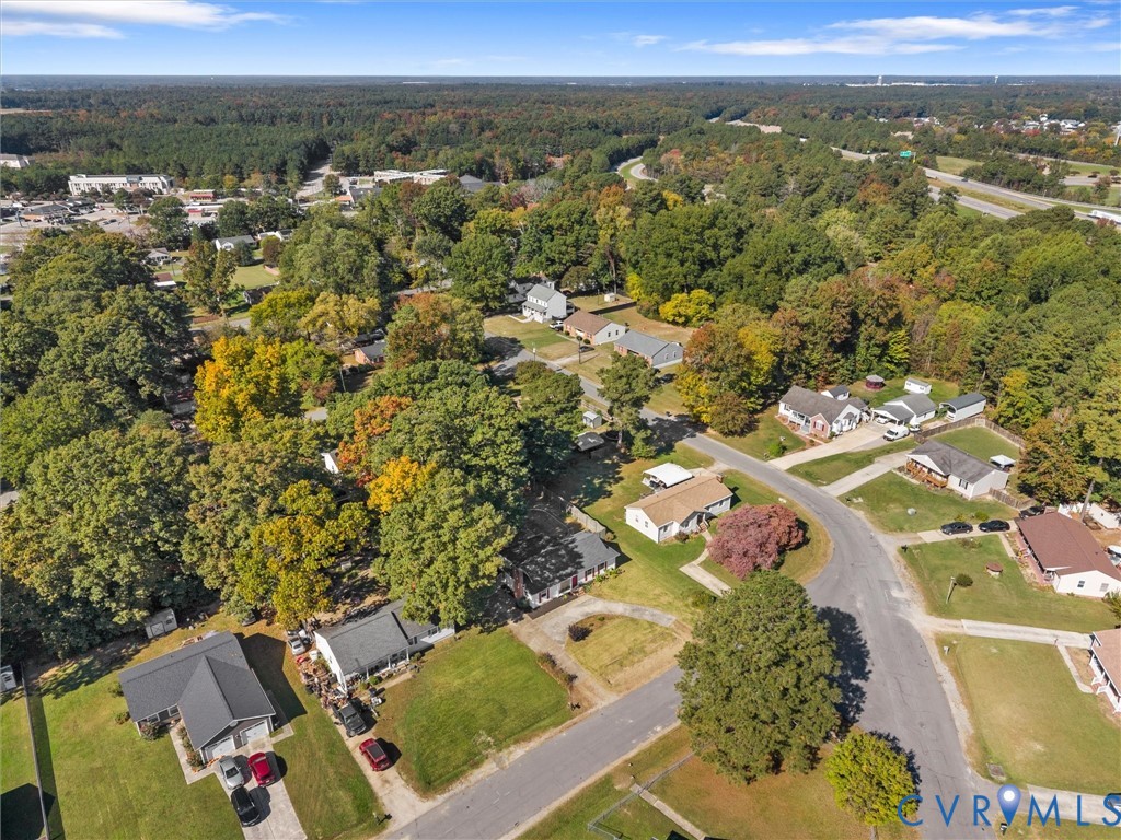 Aerial perspective of a residential neighborhood featuring established tree cover, paved roadways, and landscaped lots
