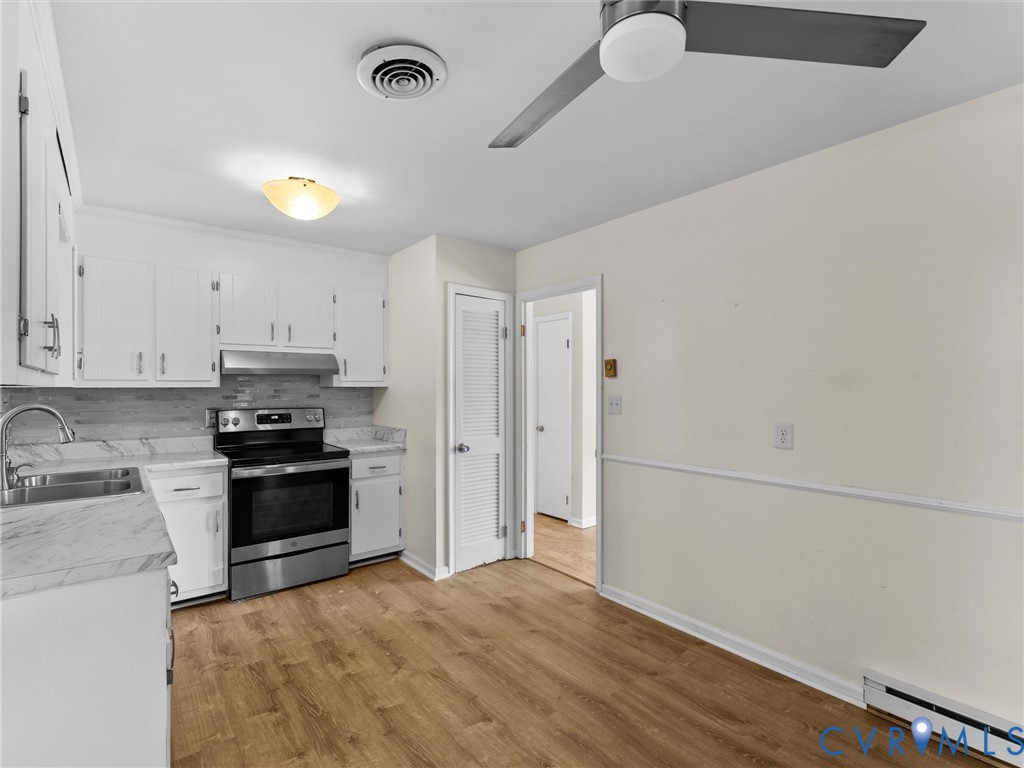 Kitchen featuring white cabinetry, stone-finish laminate countertops, stainless steel range with overhead hood, wood-finish flooring, and ceiling fan with integrated lighting