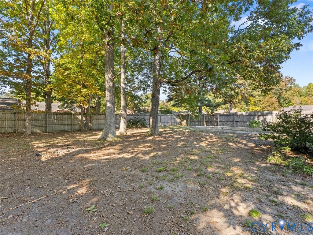 Backyard space featuring mature trees and wood-panel perimeter fencing