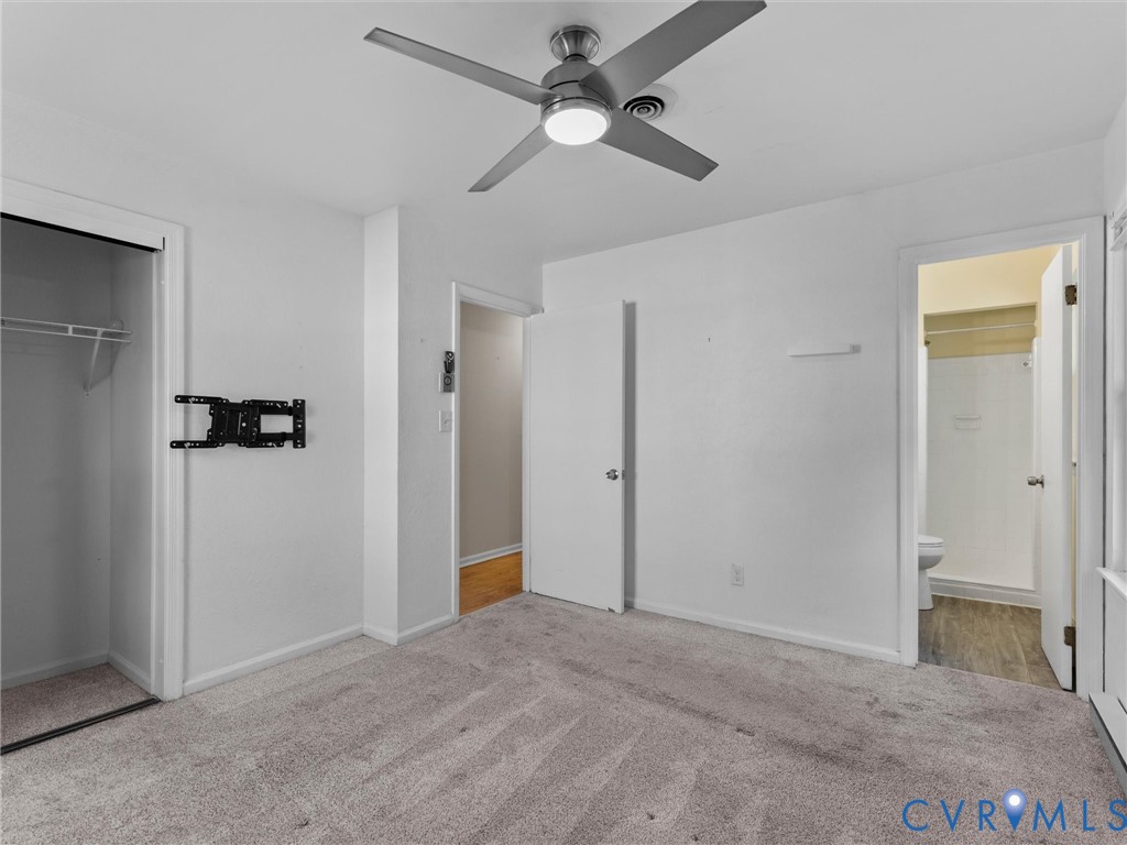 Neutral-toned carpeting, ceiling fan with integrated lighting, built-in closet, and doorway access to an interior bath