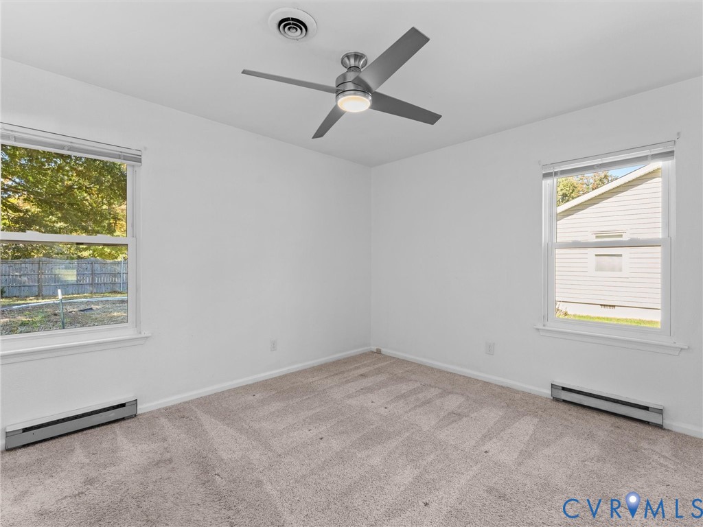 Room featuring wall-to-wall carpeting, dual windows, and a brushed metal ceiling fan with integrated lighting