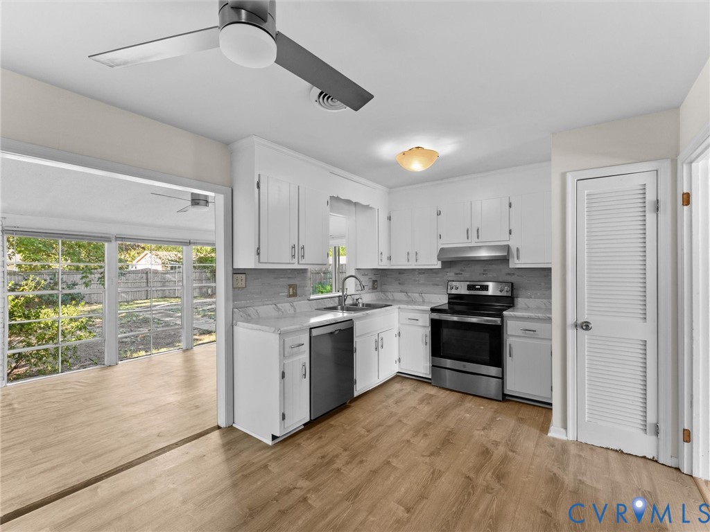 Kitchen featuring white shaker-style cabinetry, stone-finish countertops, stainless steel appliances, wood-finish flooring, and a louvered pantry door