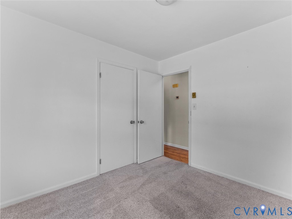 Neutral-toned carpet flooring, smooth interior walls, and dual hinged closet doors with metallic hardware