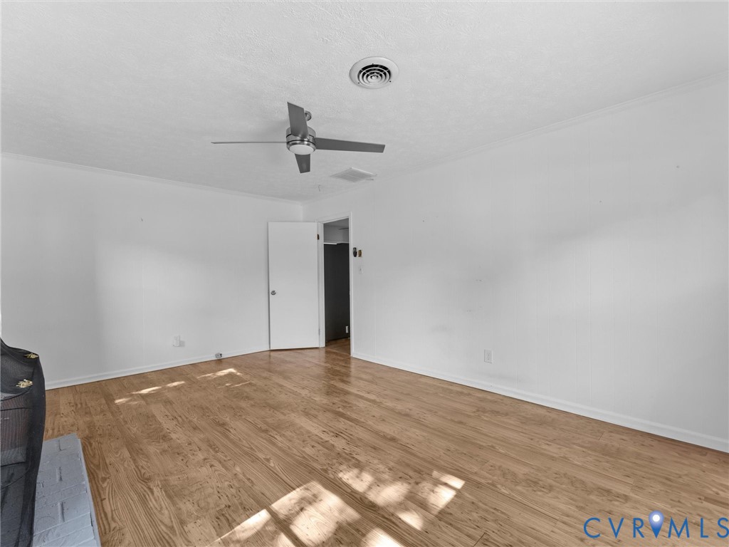 Interior space featuring wood-finish flooring, a ceiling fan with integrated lighting, and a painted brick hearth