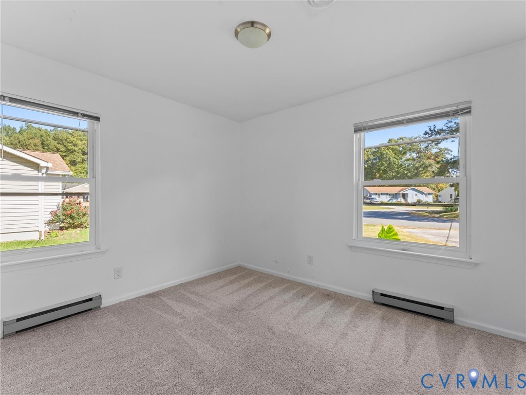 Neutral interior room featuring wall-to-wall carpeting, two double-hung windows, and a flush-mount ceiling light fixture