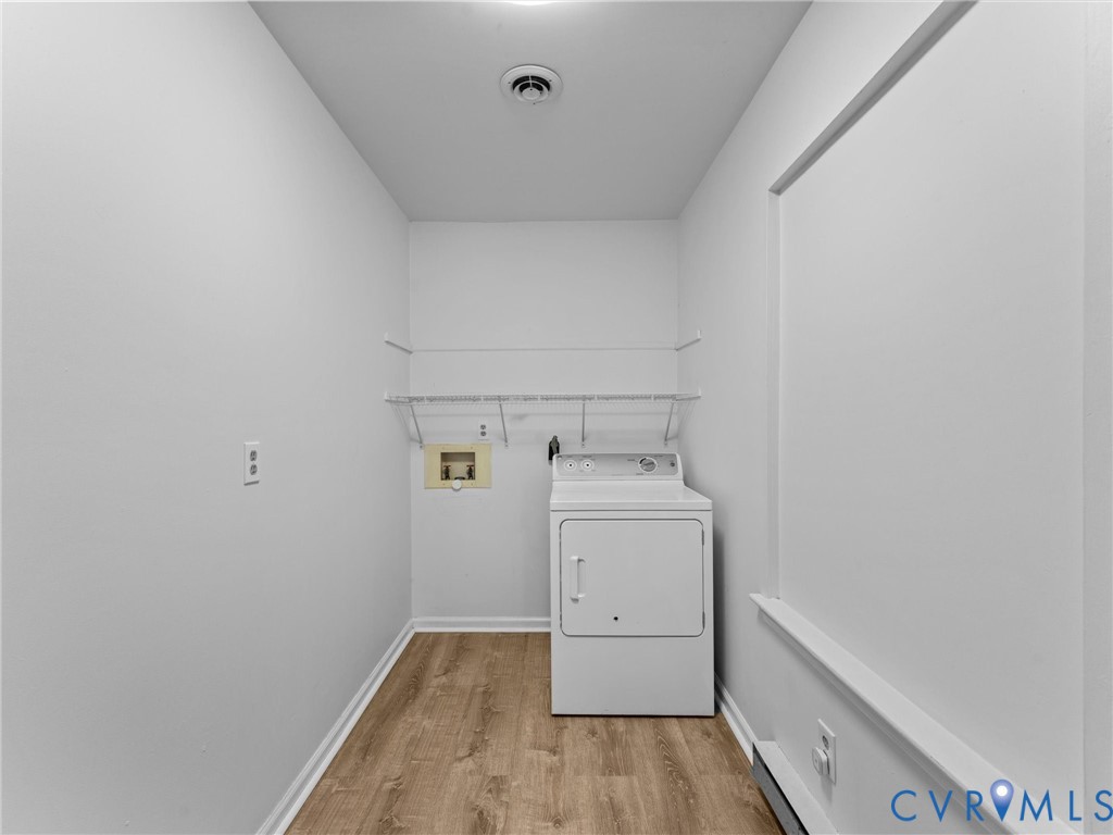 Utility space featuring wood-finish flooring, white walls, and built-in metal shelving