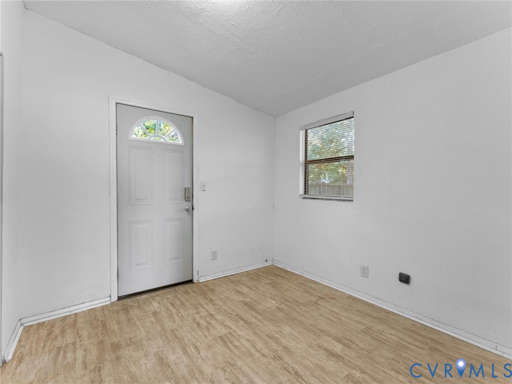 Wood-finish flooring, white walls, and a single-hung window with mini-blinds