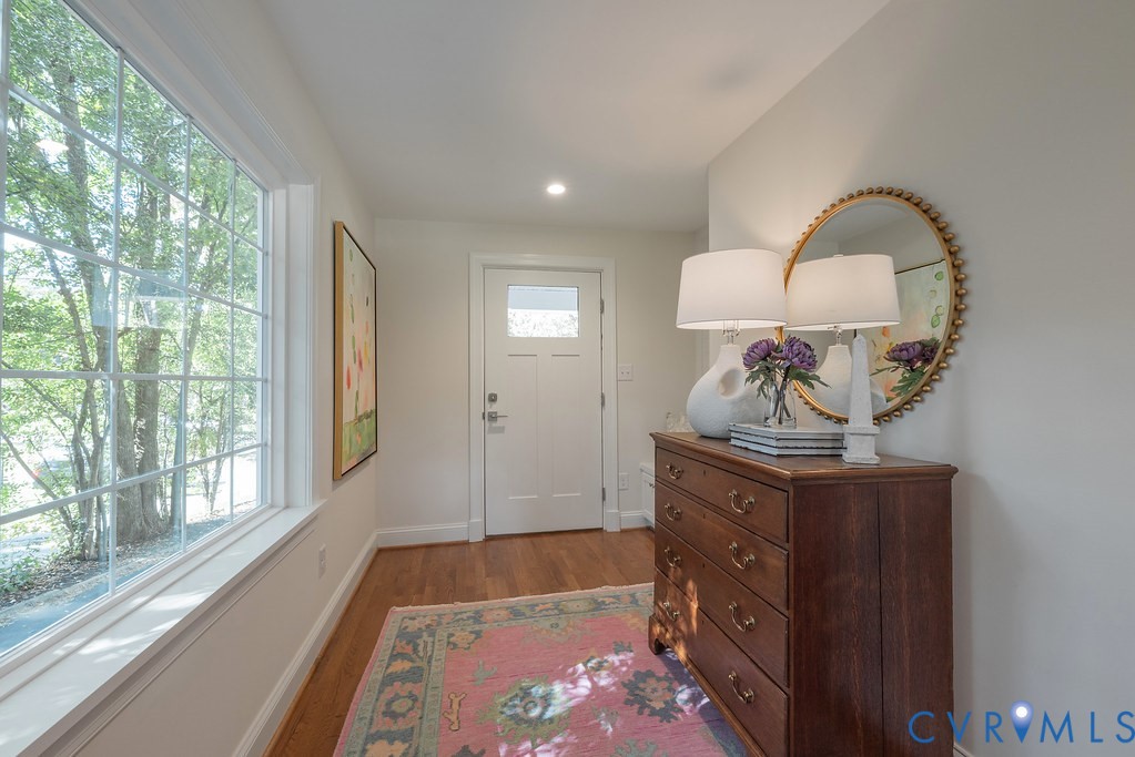 Entryway featuring wood-finish flooring, a multi-pane window, recessed lighting, and a white six-panel door with a glass insert