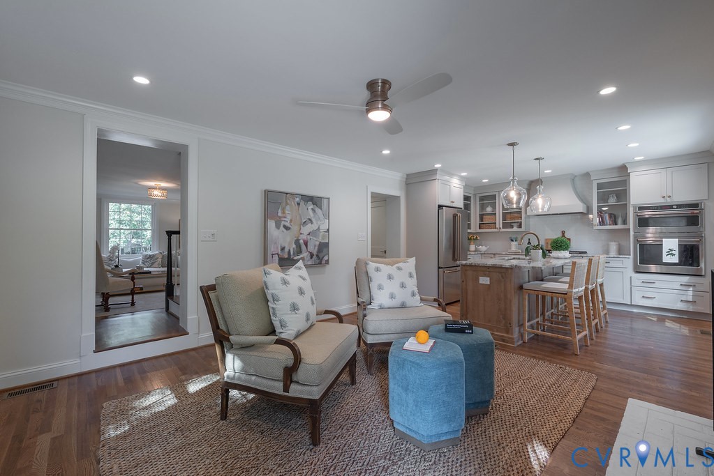 Kitchen featuring white cabinetry, wood-finish flooring, a central island with stone countertop, stainless steel double wall ovens, and recessed lighting