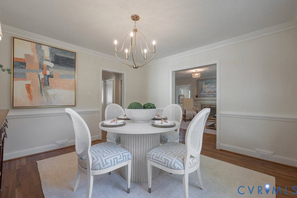 Dining space featuring wood-finish flooring, chair rail molding, and a multi-arm metal chandelier