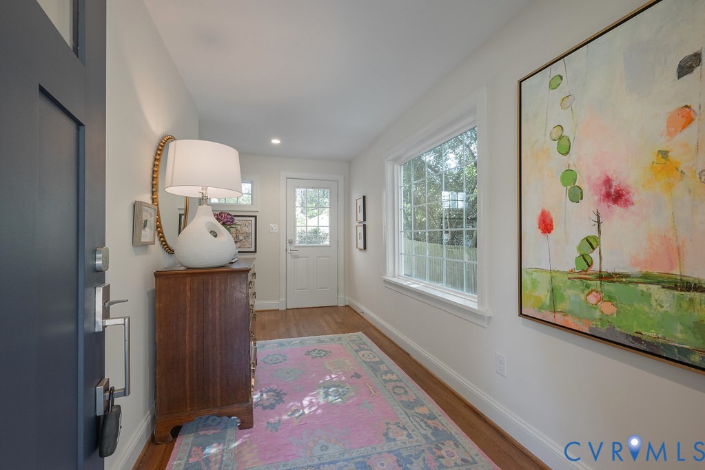 Entryway featuring wood-finish flooring, a multi-pane window, and a paneled entry door with hardware