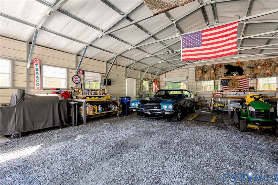 Detached metal-frame workshop featuring a gravel floor, exposed vaulted ceiling structure, and multiple windows
