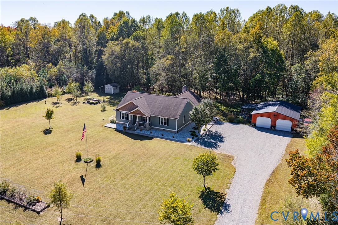 Exterior featuring a gabled roofline, lap siding, a two-car detached garage, a gravel driveway, and an expansive lawn