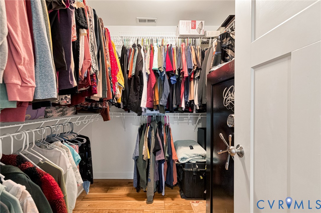 Walk-in closet featuring multi-tiered wire shelving and wood-finish flooring