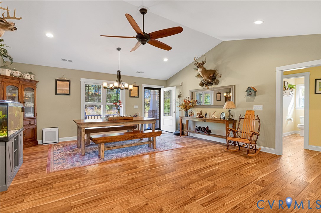 Vaulted ceilings, wood-finish flooring, recessed lighting, and a multi-arm chandelier